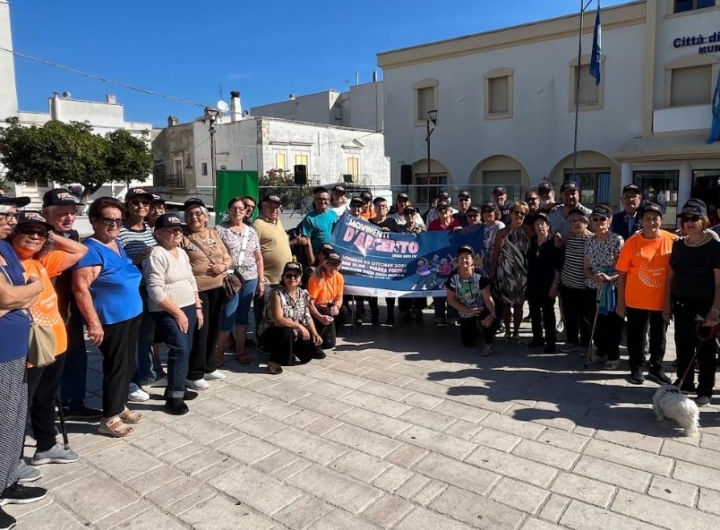 Anziani sorridenti praticano attività fisica all'aperto durante l'evento 'Movimenti d'Argento' a Peschici.