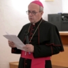 L'arcivescovo Franco Moscone, con abito talare, parla di fronte a un microfono.